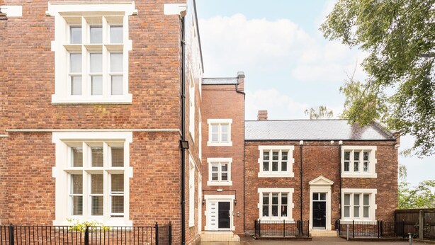 A brick building with white-framed windows and a black metal fence. - Host Stay The Cathedrals (Durham)