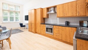 A modern kitchen with wooden cabinets, a stainless steel oven, and a black countertop. - Host Stay The Cathedrals (Durham)