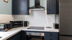 A modern kitchen with dark cabinets, a stainless steel refrigerator, a built-in oven, a microwave, and a coffee maker. - Host Stay The Quarter (Liverpool)