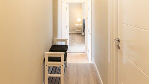 A narrow hallway with a bench, a small table with a lamp, and a door at the end. - Host Stay The Quarter (Liverpool)