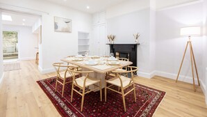 A dining room with a large table set for six, surrounded by wicker chairs, a red patterned rug, and a fireplace with decorative items. - Host Stay Hallgarth Street (Durham)