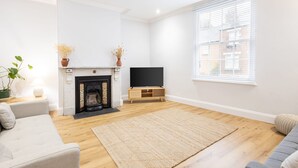 A living room with a fireplace, a flat-screen TV, and a large window. - Host Stay Hallgarth Street (Durham)