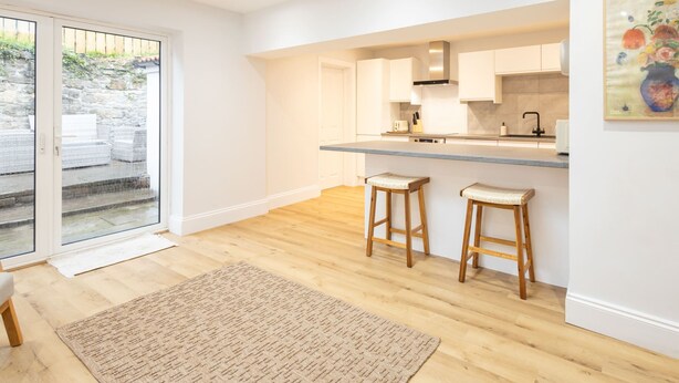 A modern kitchen with white cabinets, a wooden countertop, and two stools. - Host Stay Hallgarth Street (Durham)