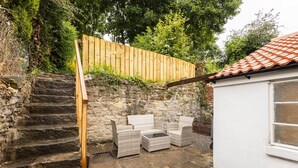 A stone staircase leading to a wooden deck with wicker furniture. - Host Stay Hallgarth Street (Durham)