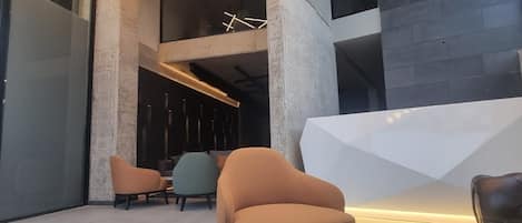 Un moderno vestíbulo con una mesa redonda de mármol, sofás de cuero e iluminación con formas geométricas.