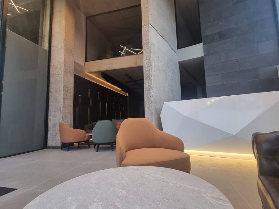 Un moderno vestíbulo con una mesa redonda de mármol, sofás de cuero e iluminación con formas geométricas.