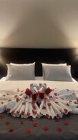 Cama bem arrumada com lençóis brancos e um arranjo decorativo de rosas e flores.