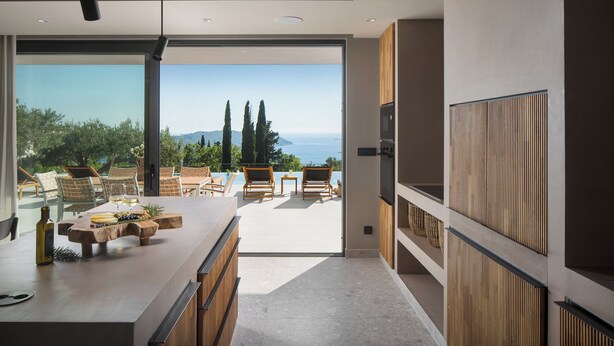 A modern kitchen with a large island, wooden cabinets, and a view of the sea. - Lavish Villa O with Panoramic Elefiti Islands View, Six Bedrooms with a Pool (Dubrovnik)