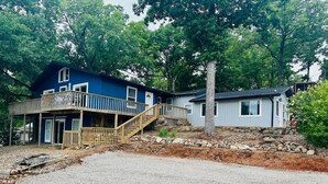 A two-story house with a wooden deck and a stone staircase leading to the entrance. - Terrific lake view! On the shoreline. (Sunrise Beach)