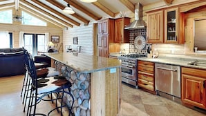 Una cocina amplia con armarios de madera, una isla grande con taburetes de bar, una estufa y un lavavajillas.