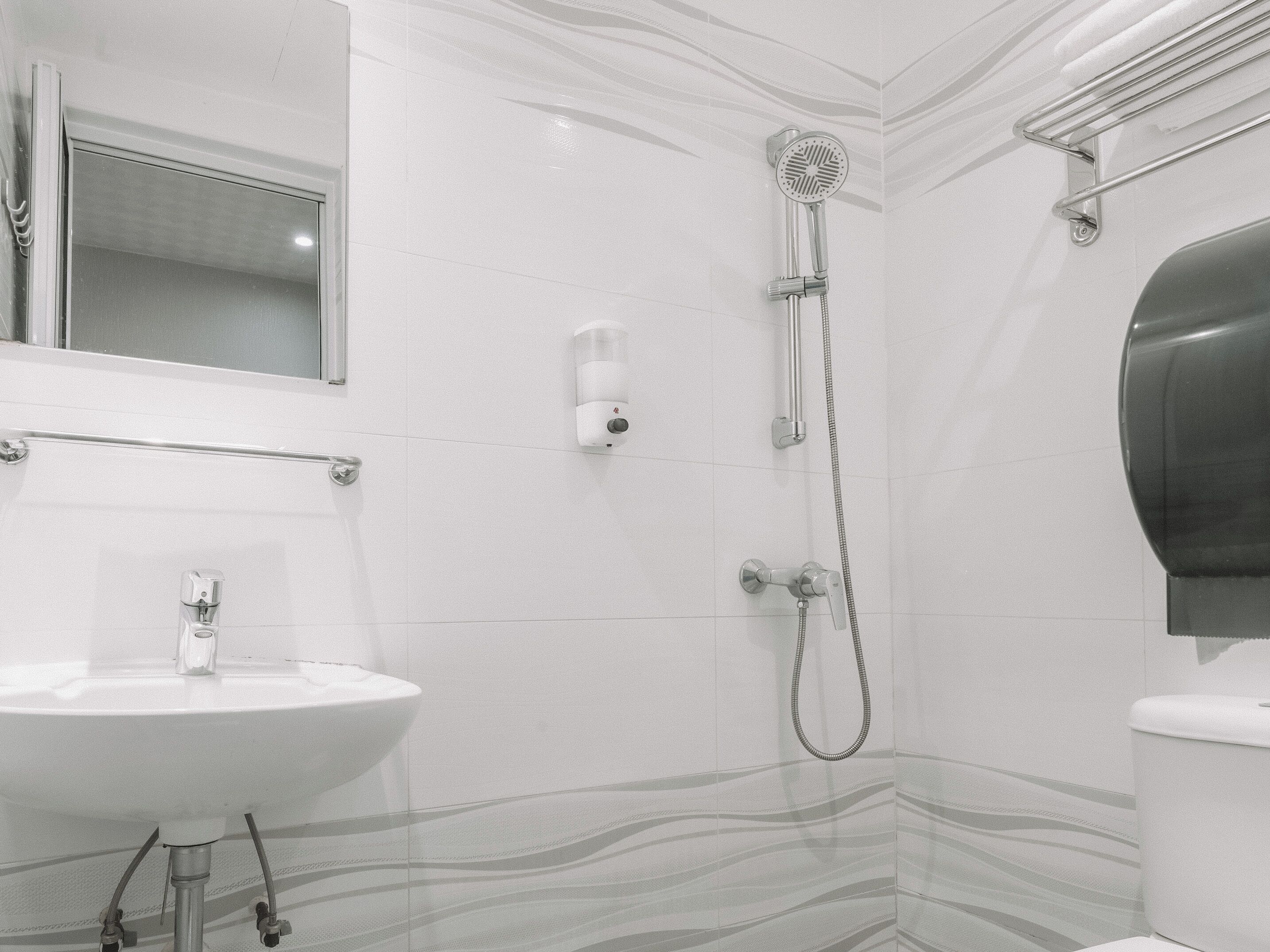 Et badeværelse med en hvid vask, brusehoved og toilet.