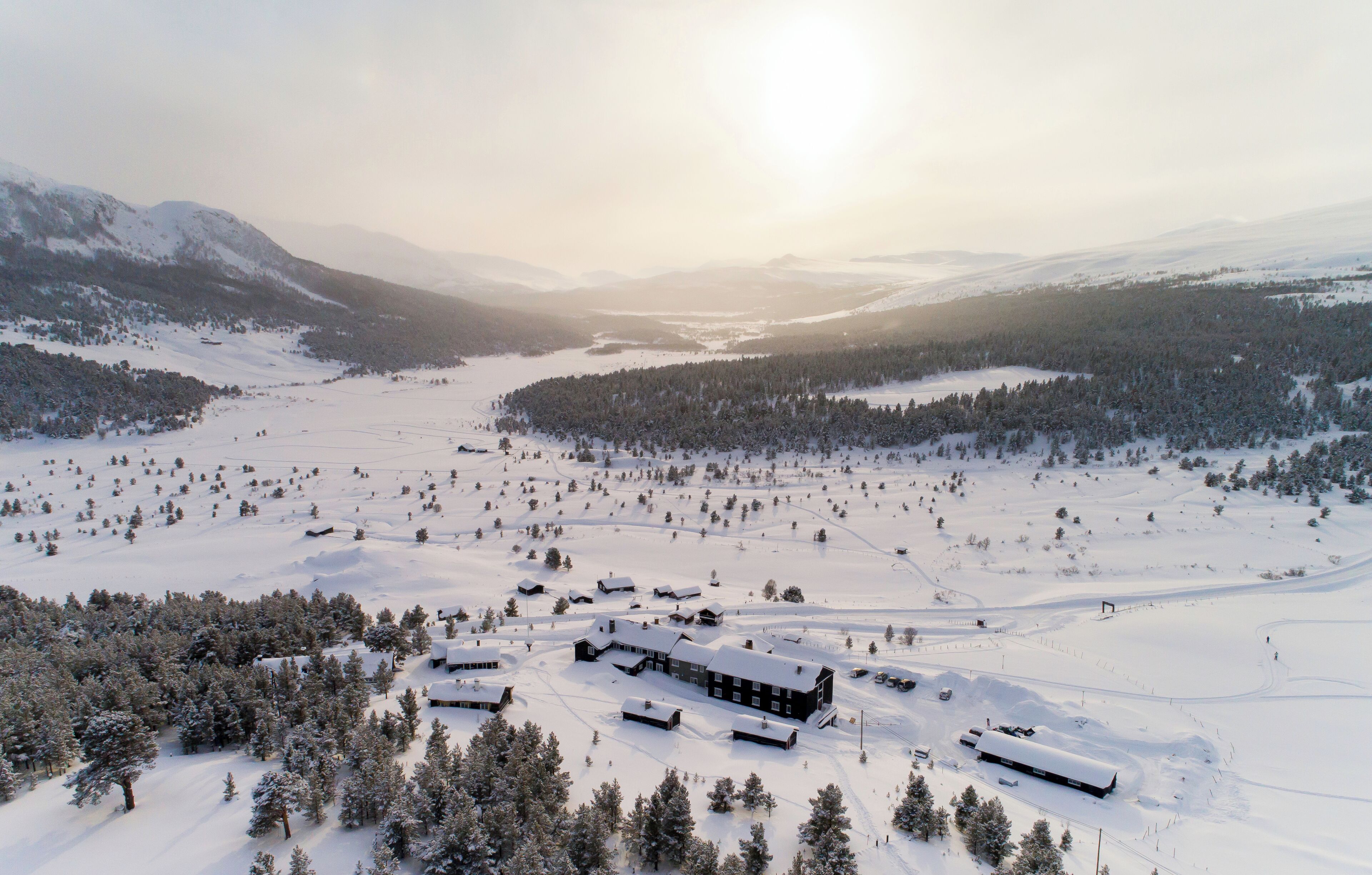 Paisaje nevado con una cabaña y algunas cabañas.