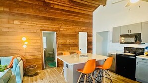 A modern kitchen with wooden walls, a central island, and orange chairs. - Astonishing view 100 feet from the lake! (Sunrise Beach)