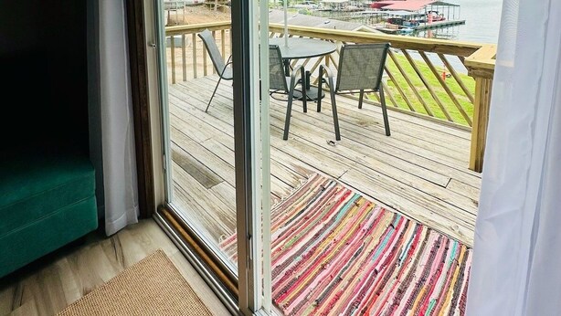 A room with a large sliding glass door leading to an outdoor deck with a view of a lake and dock. - Astonishing view 100 feet from the lake! (Sunrise Beach)