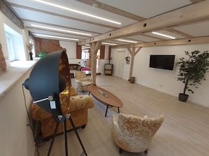 A spacious room with a modern ceiling design, a television mounted on the wall, and a potted plant. - Alter Speicher (Schönberg)