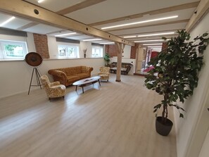 A spacious room with a wooden floor, a large sofa, two armchairs, a coffee table, and a potted plant. - Alter Speicher (Schönberg)