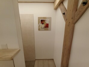 Un couloir étroit, avec un cadre de porte en bois et un petit tableau encadré accroché au mur.