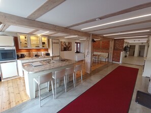 Une cuisine moderne dotée d’un îlot central, de tabourets de bar blancs et d’un tapis rouge menant à un coin repas.