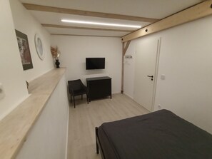 Une chambre à coucher avec un lit, une télévision, un bureau et une chaise.