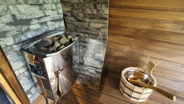 Une cuisine moderne avec un mur recouvert de pierres apparentes, une cuisinière en acier inoxydable et un saladier en bois avec une cuillère.