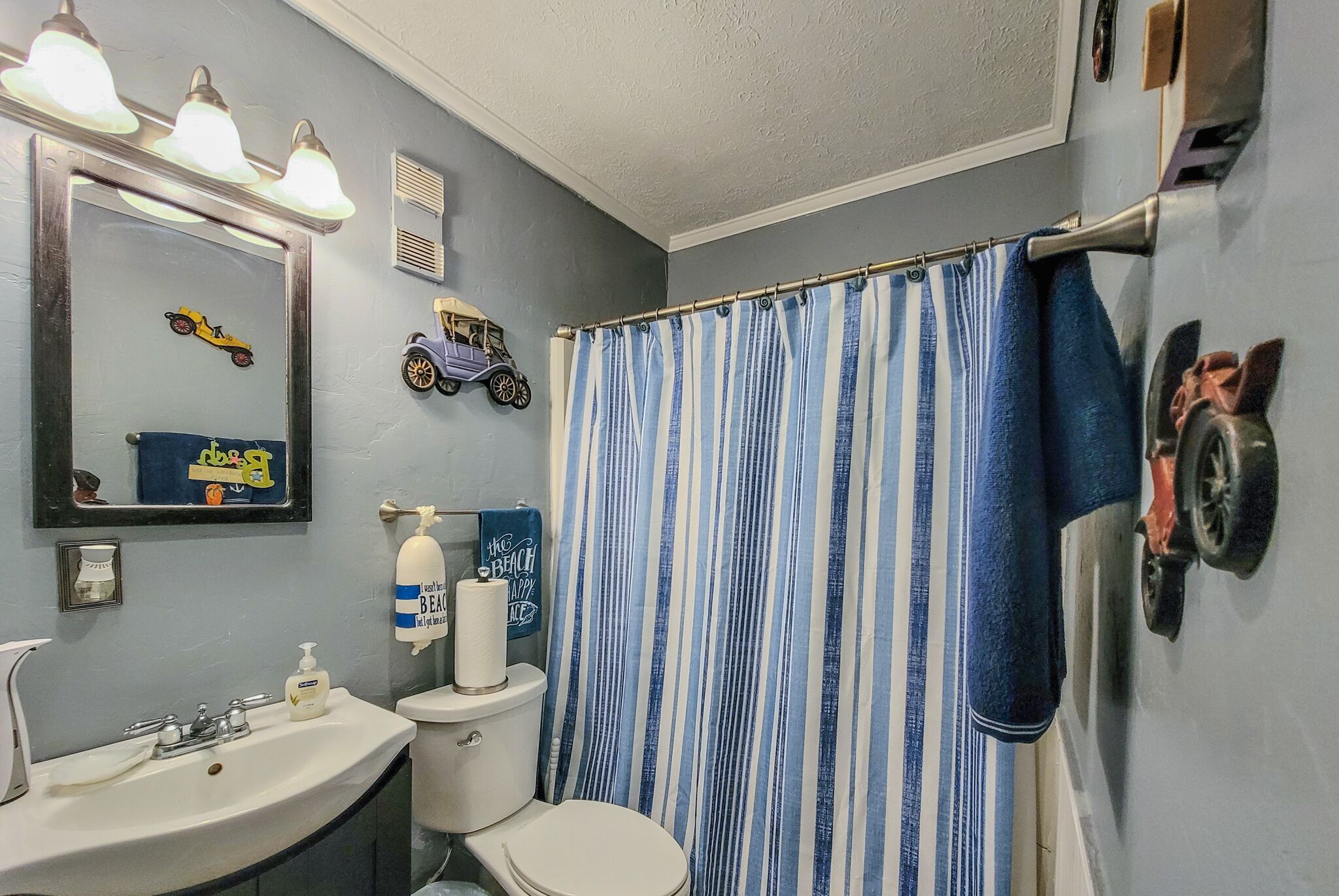 Un bagno con lavandino, water e tenda per la doccia.