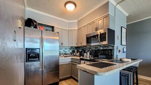A modern kitchen with stainless steel appliances, a central island, and a microwave. - Topsail Reef 358: Dream2B - Oceanfront Getaway! (North Topsail Beach)