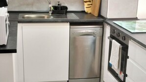 A modern kitchen with white cabinets, a stainless steel dishwasher, a built-in oven, and a black microwave.