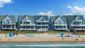 Una propiedad frente a la playa con casas de varios pisos, balcones y grandes ventanales.
