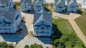 Una zona residencial costera con varias casas de dos pisos, techos a dos aguas y porches delanteros.