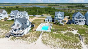 A coastal property with multiple large houses, a swimming pool, and a beach area. - Elegant Beach Villa: Pool, Hot Tub, Ocean Views (North Topsail Beach)