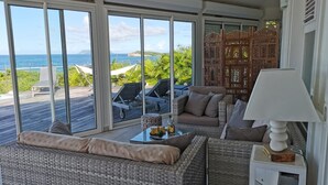 A cozy room with wicker furniture, a table with drinks, and a view of the ocean.