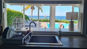 A kitchen with a view of a pool and the ocean.