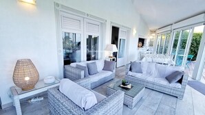 A spacious outdoor living area with wicker furniture, a table, and a lamp.