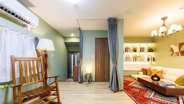 A living room with a wooden rocking chair, a sofa, a coffee table, and a patterned rug. - Sky Building Umeda (Osaka)