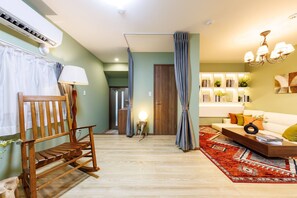 Un salon comprenant un fauteuil à bascule en bois, un canapé, une table basse et un tapis à motifs.