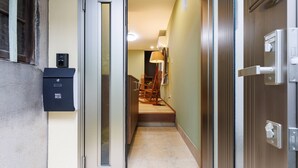 A hallway with a mail box, a wooden staircase, and a door with a handle. - Sky Building Umeda (Osaka)