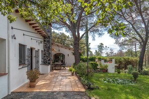 A house with a patio, a garden with a pond, and a tree.