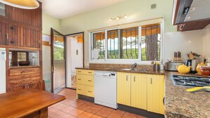 A kitchen with wooden cabinets, a dishwasher, a window with a view, and a dining table. - Charming Home in a Green Valley. El Pigot. Tranquility, Nature & Private Pool! (Riudarenes)