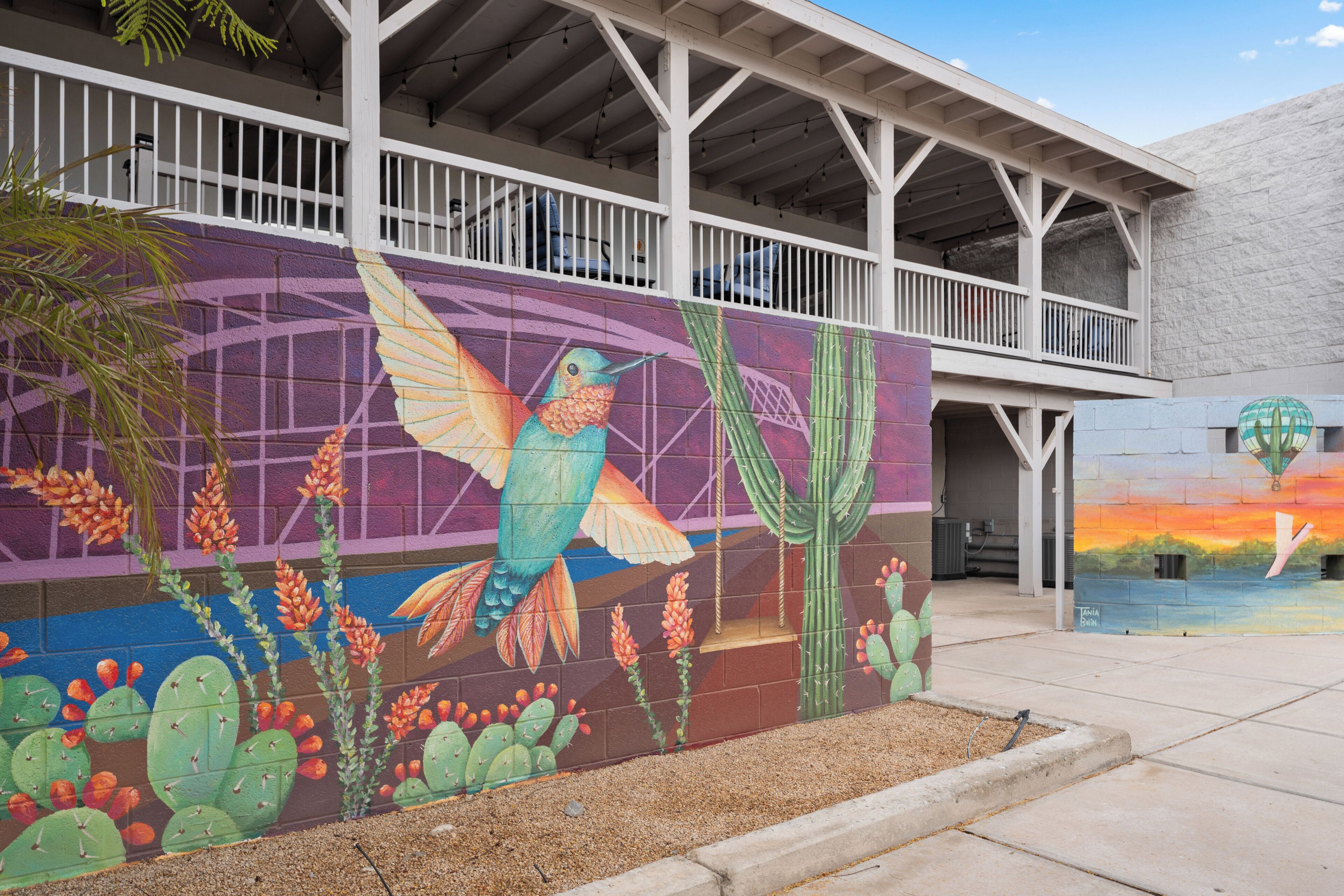 Un bâtiment orné d’une fresque représentant un colibri et des cactus.