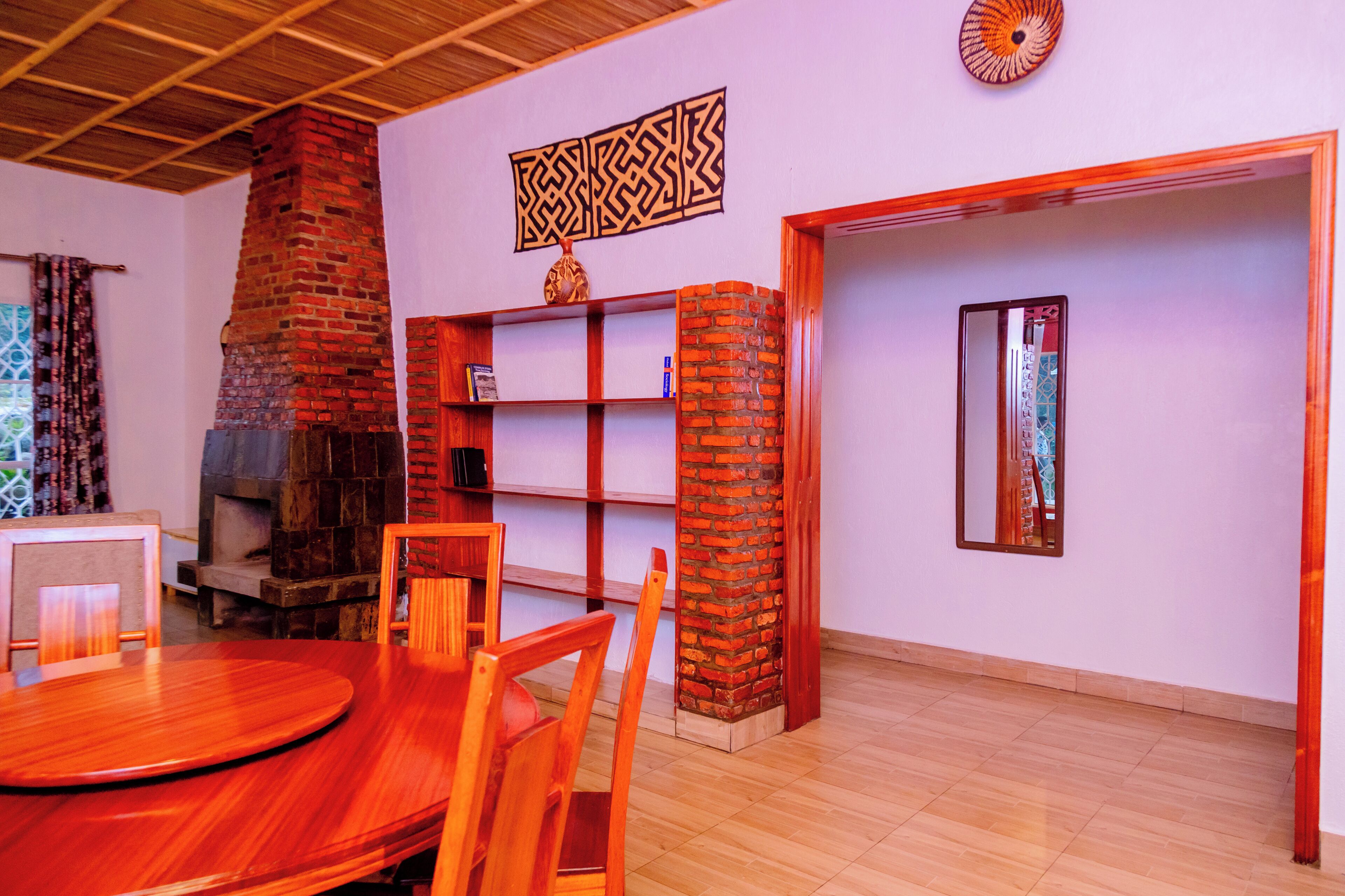 A room with a brick fireplace, wooden furniture, a bookshelf, and a mirror.