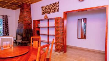 A room with a brick fireplace, wooden furniture, a bookshelf, and a mirror.