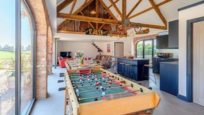 Una habitación amplia con mesa de fútbol, zona de bar y vistas al exterior.