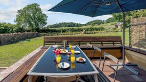 Un área de comedor al aire libre con una mesa dispuesta para el desayuno, que incluye croissants, jugo y una botella.