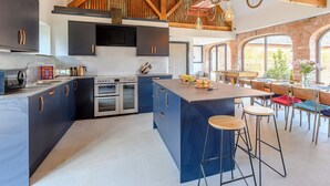 Una cocina amplia con armarios oscuros, una isla grande y un techo de madera rústica.