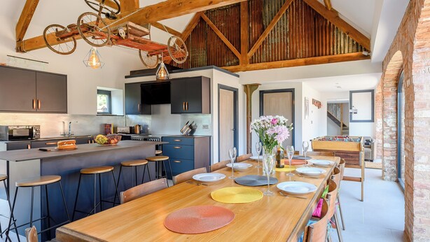 Una cocina amplia con electrodomésticos modernos, una isla grande con taburetes de bar y un techo de madera rústica.