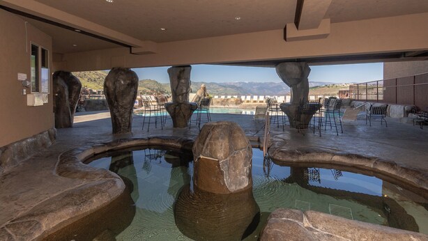 Zona de piscina con formaciones rocosas y mobiliario exterior.
