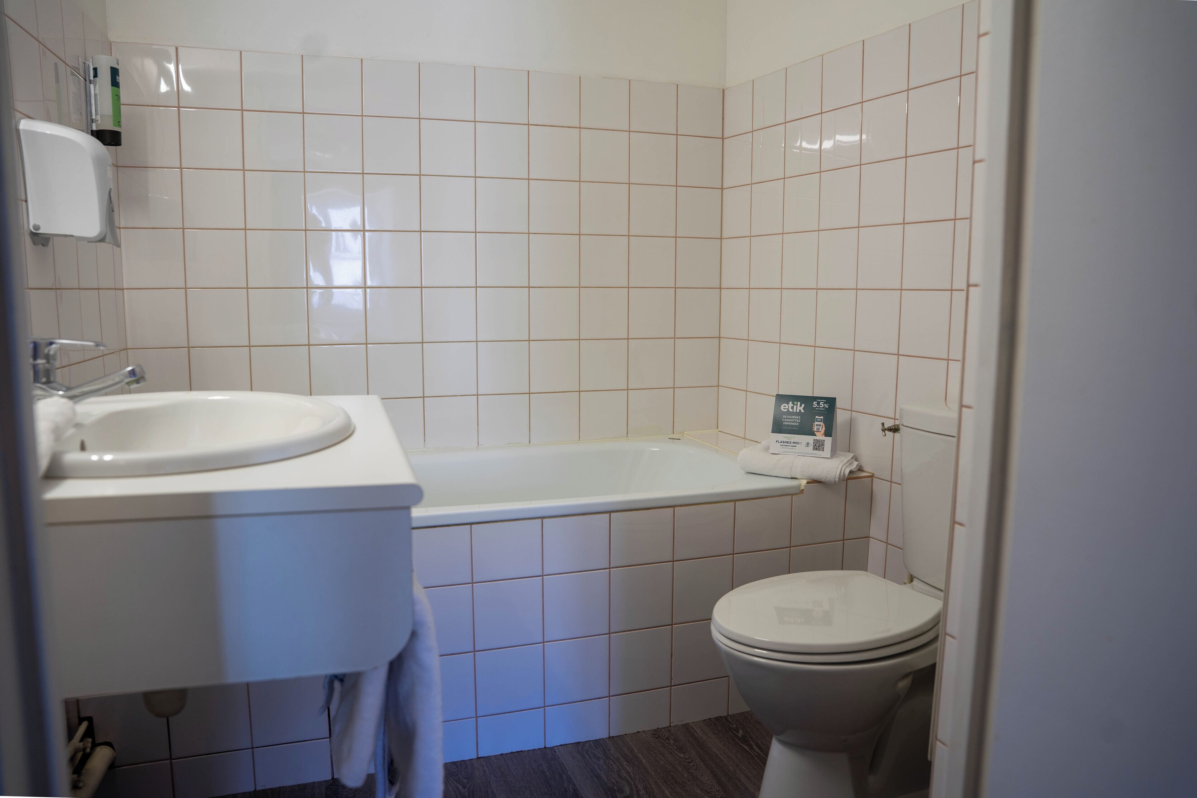 A bathroom with a white sink, a bathtub, and a toilet.