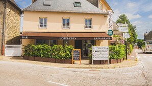 A hotel with a bar and restaurant on the ground floor, a signboard with directions, and a cobblestone street. - Logis Hôtel EBEN (Egletons)