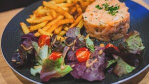 A plate of food including fries, a salmon patty, and a mixed green salad. - Logis Hôtel EBEN (Egletons)