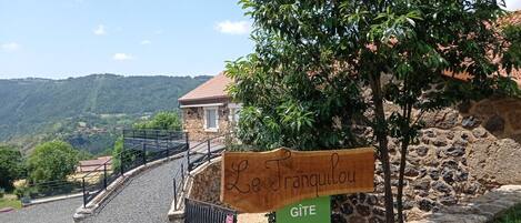 A sign for Le Frangoulou with a stone building in the background.